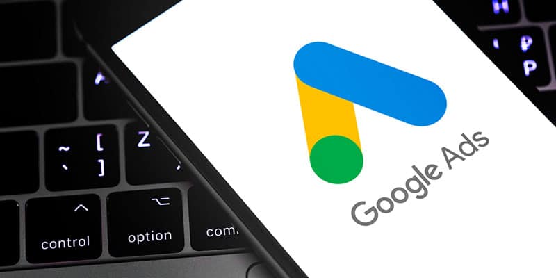 Business owner boots up Google Local Services ads on his phone in front of the computer.