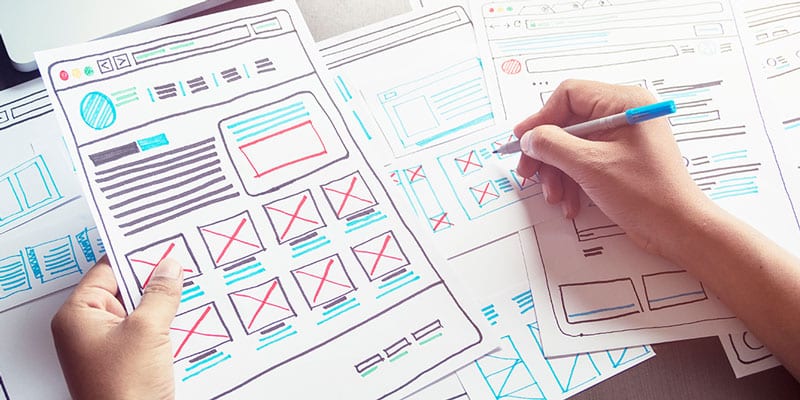 Graphic designer plans website design based on optimal user experience with pen and paper.