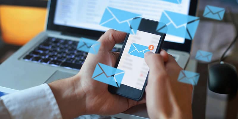 Customer opens email marketing on his smartphone in front of computer.