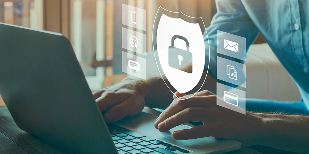 Man in blue shirt types on laptop with icons for web security popping up on screen.