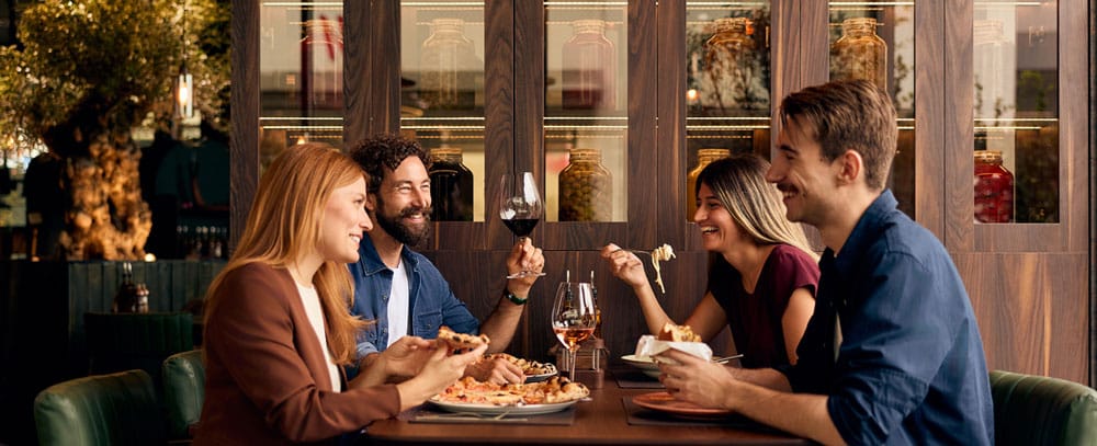 Four friends, two male and two female, sit down for a nice dinner with wine and laughs.